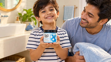Boy holding a jar of Dirty Good Nautical Breeze Kids Body Wash, his father beside him with a towel