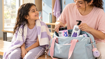 Girl with damp hair after swim class as her mother packs Dirty Good Cotton Candy Kids Body Wash and Tangle Free Conditioning Shampoo, the pair in the Dream Bath Duo