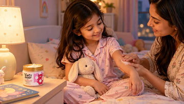 Mother smoothing on Dirty Good Pink Petal Kids Body Butter as her daughter sits on the bed in pyjamas at bedtime