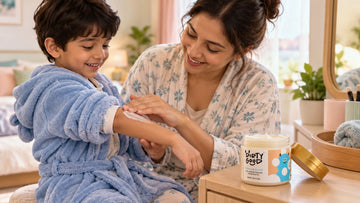 Mother smoothing Dirty Good Vanilla Kids Body Butter onto her son's arm after bath time