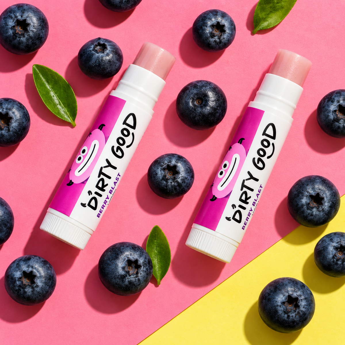 Two Berry Blast chapsticks with blueberries on pink and yellow